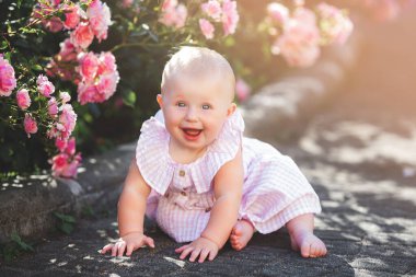 Dışarıda şirin bir bebek var. Gülleri olan sevimli küçük bir kız. Bahçedeki güzel çocuk..