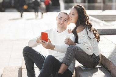 Genç, çok ırklı bir çift cep telefonuyla selfie çekiyor. Erkek ve kadın birlikte eğleniyor. Gençler akıllı telefonda konuşuyor..