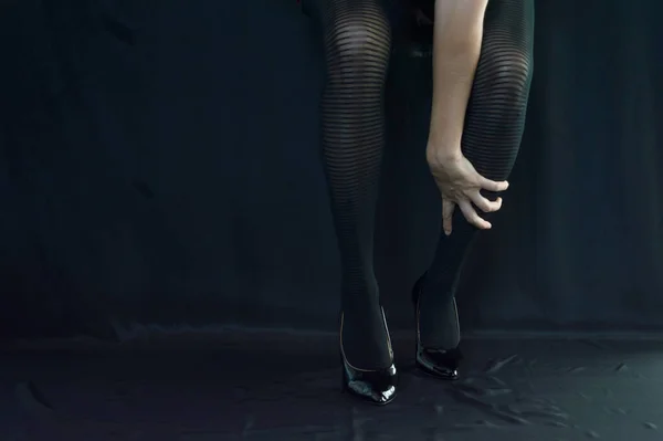 女腿在黑色底座上穿着黑色裤袜 一只手放在一只腿上的女腿 — 图库照片