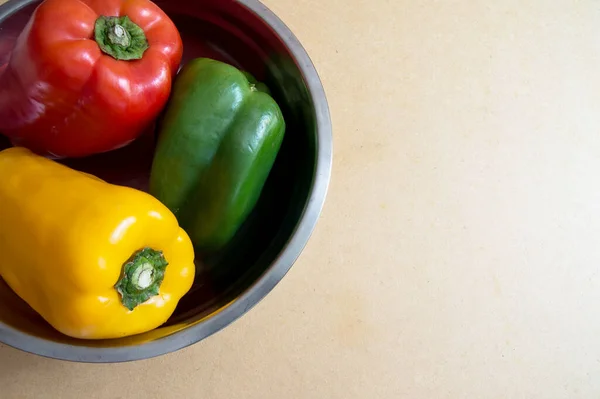 Bell peppers, red, green, and yellow peppers inside metal bowl photographed from above