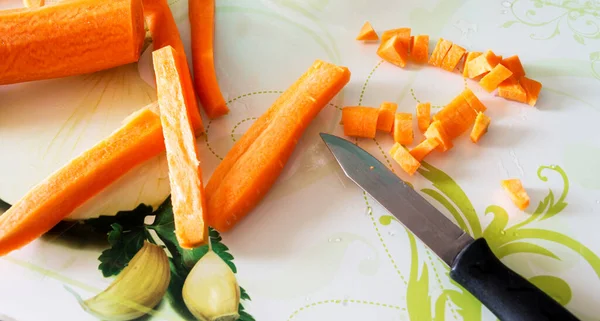 Raw carrots chopped into small pieces and strips with knife photographed from above