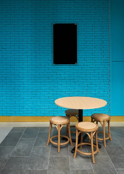 Tables and chairs at sidewalk cafe with blue brick wall