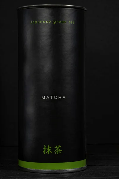 Siyah zemin üzerinde Japon yeşil çayı olan alüminyum kavanoz.