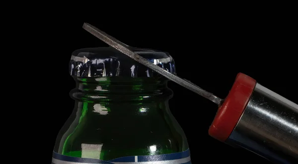 opening a metal bottle cap with a bottle opener. High quality photo