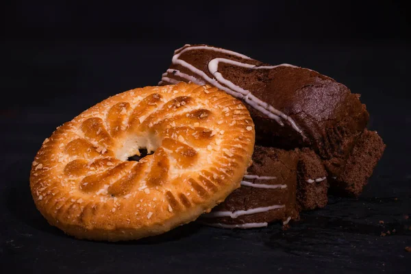 Sliced chocolate biscuit roll with chocolate biscuits on a black background. High quality photo