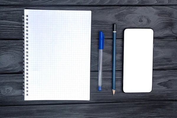 Top view of the coffee cup and notepad with pen and empty smartphone on the wooden table. . White empty space for advertise text