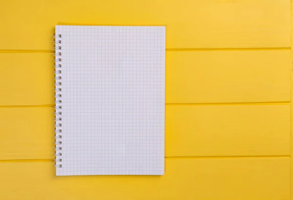 top view white notebook on a paper clip on a yellow background. High quality photo