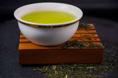 Elinde çay yaprakları olan ahşap bir büfede kulpsuz bir fincan. Yüksek kalite fotoğraf