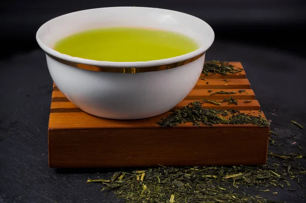 Elinde çay yaprakları olan ahşap bir büfede kulpsuz bir fincan. Yüksek kalite fotoğraf