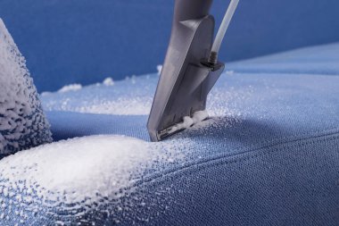 Elektrikli süpürgenin fırçası mavi kanepeden köpük topluyor.