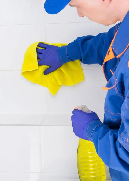 a cleaning company employee washes ceramic tiles in the bathroom