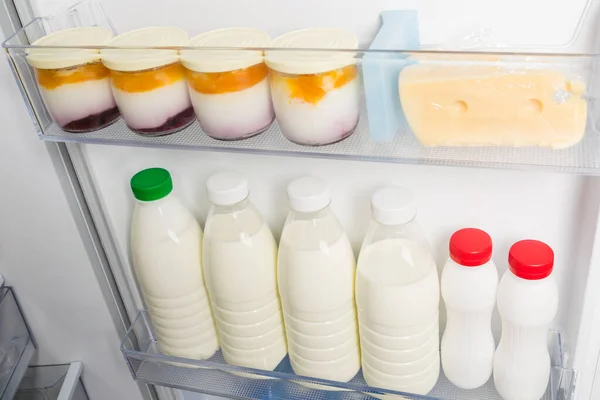 milk and dairy products are on the shelves in the refrigerator door, close-up view