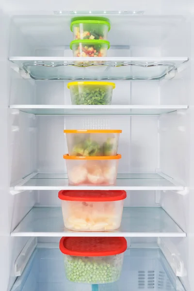 storage containers filled with vegetables are in a row in the refrigerator