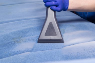 Kanepedeki kiri temizlemek için elektrikli süpürgeye yakın çekim.