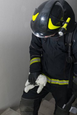 Bir itfaiyeci merdivenleri tırmanır, elinde oyuncak bir oyuncak ve kapı açmak için bir balta taşır.