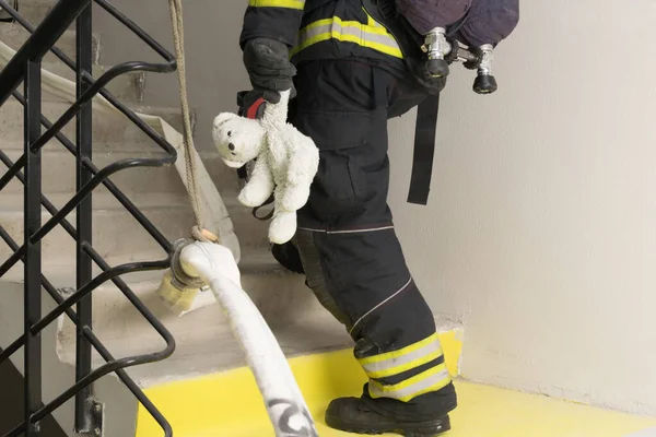 Firefighter Climbs Stairs Holding Teddy Bear Toy His Hand — Stock Photo, Image