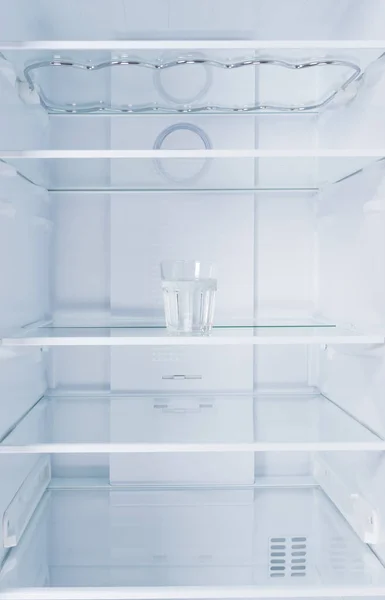 Beyaz Bir Buzdolabının Arka Planında Cam Bir Rafta Bir Bardak — Stok fotoğraf