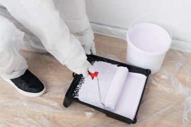 Bir işçi tepsiden silindire boya sürer.