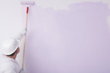 a worker paints the wall purple, on the right is a place for your inscription