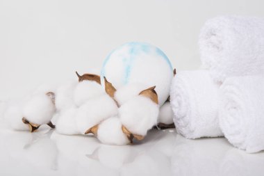 Yansıması olan beyaz bir masada, kaplıca tedavileri için havlular sarılmış ve banyo tuzu şeklinde bir top şeklinde, yakın çekim.