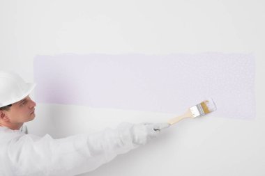 silindirli bir adam beyaz bir duvarı farklı bir renge boyamaya başlar.