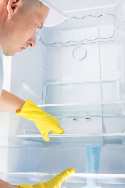 Temizlik servisinden bir adam evdeki buzdolabının içinde yıkanır.