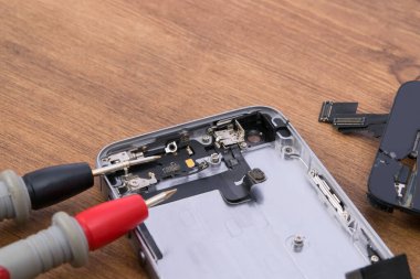 Ahşap bir masa üzerinde, yakın çekim, sorun giderme akıllı telefon testçisini kullanarak aküyü tamir etmek ve değiştirmek için