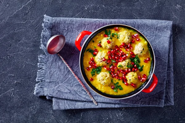 Ash-e Anar, Persian Split Pea Pomegranate Soup with lamb Meatballs in a red pot on a concrete table, horizontal view from above, flat lay, close-up