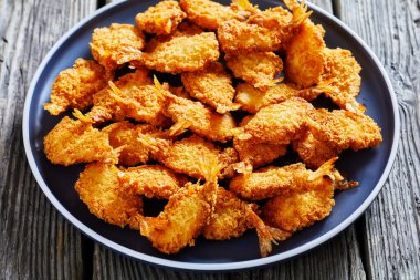 Crispy Deep Fried Butterfly Shrimp on a grey plate on a textured rustic wooden table, horizontal view from above, close-up clipart