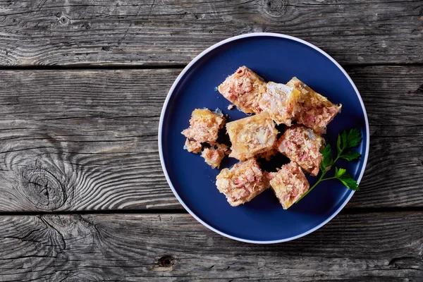 meat aspic, jellied slow cooked meat on a plate on a rustic wooden table,  flat lay, free space