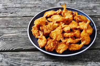 Crunchy Fried Butterfly Shrimp on a grey plate on a textured rustic wooden table, horizontal view from above clipart