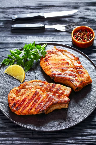 Grilled Bone Pork Chops Black Plate Lemon Slice Parsley Wood — Stock Photo, Image