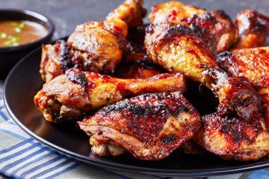 grilled brown sugar glazed chicken thighs and legs on a black plate, close-up clipart