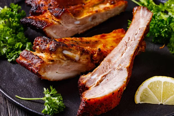 Juicy Roast Pork Ribs Black Plate Dark Wooden Table Horizontal — Stock Photo, Image