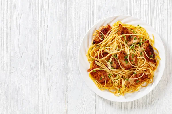 Fried  turkey breast with gluten free pasta on white plate on white wooden table, horizontal view from above, flat lay, free space