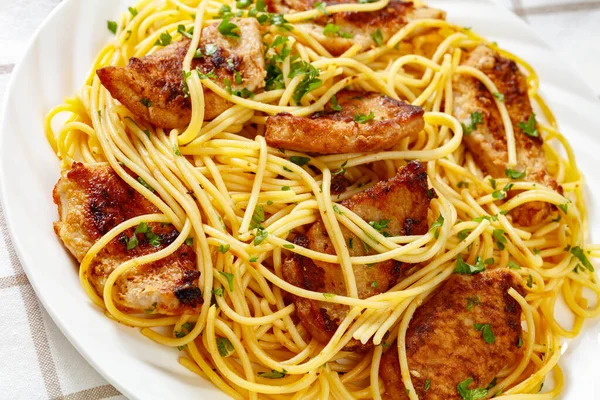 close-up of Fried  chicken breast with gluten free pasta on white plate on white wooden table, horizontal view from above