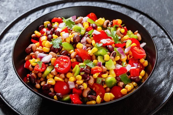 Black Bean Salad with Black-Eyed Peas, pepper, red onions, corn, cherry tomatoes and cilantro in black bowl