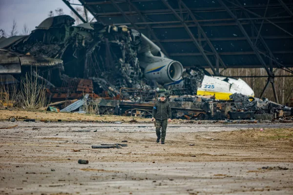 Hostomel, Ukrayna. 08 Nisan 2022 Ukrayna askeri Ukrayna 'ya yapılan Rus işgali sırasında Hostomel havaalanında imha edilen Ukraynalı Mriya AN-225' in arka planında yürüyor.