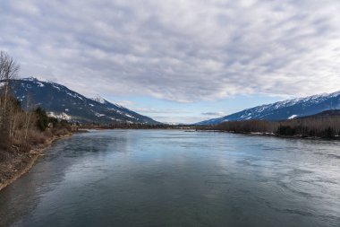 Dağlarda karla kaplı geniş Kolombiya nehri mavi gökyüzü İngiliz Kolombiyası Kanada ilkbaharı.