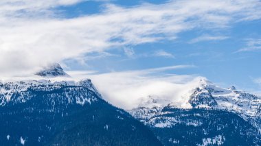 Büyük dağlar karla kaplı ve bulutlu güneşli gökyüzü Britanya Kolombiyası Kanada.