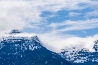 Büyük dağlar karla kaplı ve bulutlu güneşli gökyüzü Britanya Kolombiyası Kanada.