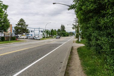 SURREY, CANADA - MAY 28, 2020: street view with road commercial buildings cloudy day clipart