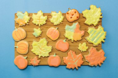 Ahşap tahtada kremalı, mavi arka planda düz kompozisyonu olan ev yapımı tatlı kurabiye.