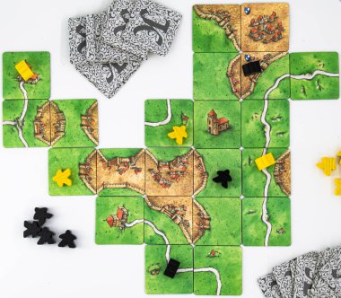 Carcassonne masa oyunu beyaz arkaplanda sarı ve siyah meeple ile oynandı