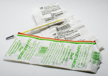 Beyaz arka planda termometre, parasetamol ve aspirin.