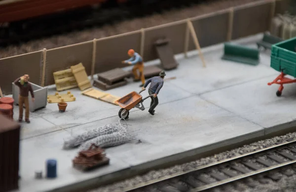 Miniature shows worker pulls a trolley for building materials