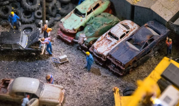 Model düzeni. Hurdalıkta paslı arabaları teftiş eden adamlar.