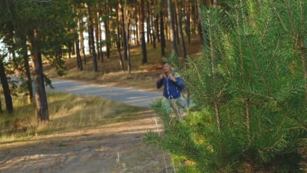 Зрілий чоловік мандрівник з рюкзаком ходить в осінньому лісі біля річки — стокове відео