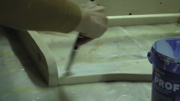 Eine Frau gießt Farbe ein und bereitet sich darauf vor, ein Holzregal zu bemalen. Geschäftsmöbelfertigung — Stockvideo