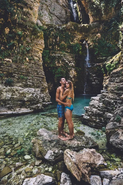 Casal jovem em abraço na cachoeira selvagem — Fotografia de Stock